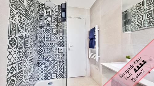 La salle de bains est pourvue d'une douche et d'un mur en carrelage noir et blanc. dans l'établissement Les Suites Mulhousiennes - Charme & Sérénité, à Mulhouse