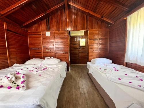 two beds in a room with wooden walls at Imeros Hotel Beldibi in Beldibi