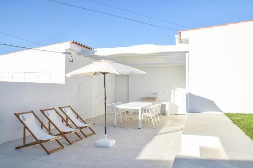 a patio with a table and chairs and an umbrella at Casa Vista Verde by LovelyStay in Sesimbra
