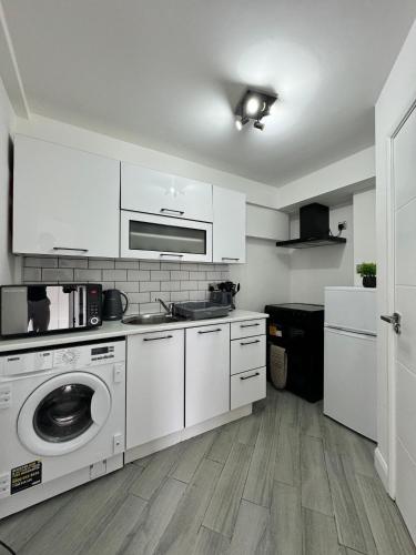 a kitchen with white cabinets and a washing machine at Westminster Guest House in Oxford