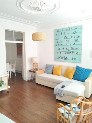 a living room with a couch and a painting on the wall at Bird's Nest Lisbon Apartment in Lisbon