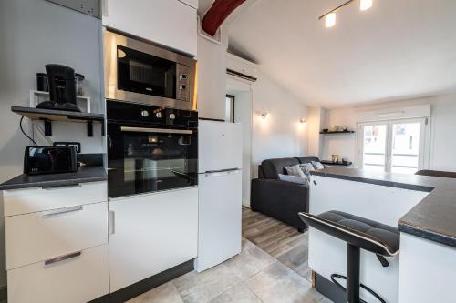 une cuisine avec des armoires blanches et un four à plaques de cuisson dans l'établissement Charmant T3 climatisé proche Paris, à Romainville