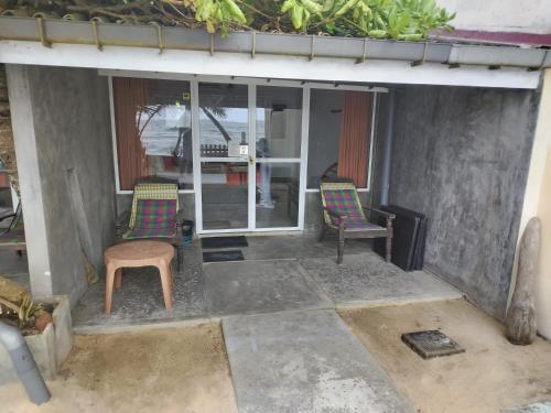 a patio with two chairs and a table at Happy Beach Resort in Unawatuna