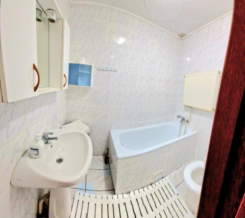 a white bathroom with a sink and a bath tub at Casa Kati in Buşteni