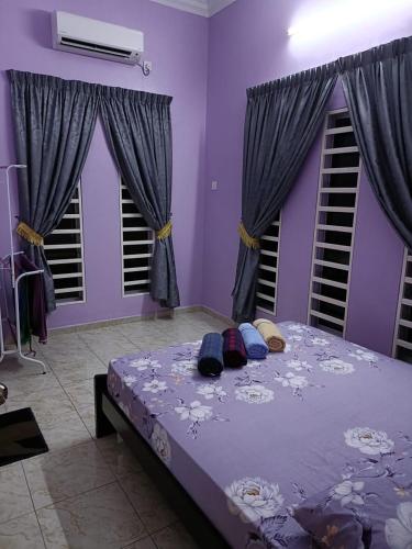 a bedroom with a bed with purple walls and windows at Larut Tin Homestay in Taiping