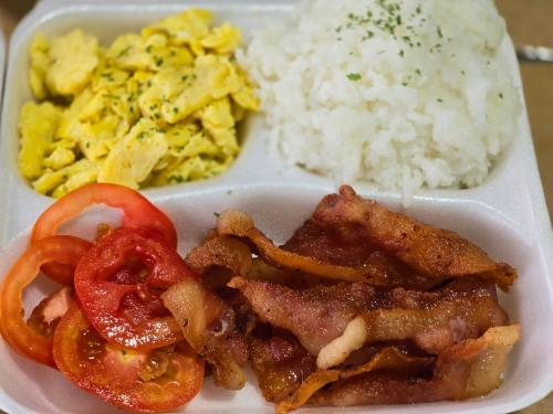 a styrofoam plate of food with bacon tomatoes and rice at D' Kikays Saekyung Village 1 in Basbas