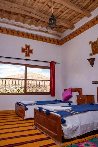 a bedroom with two beds and a large window at Hotel Awayou in Bou Tharar