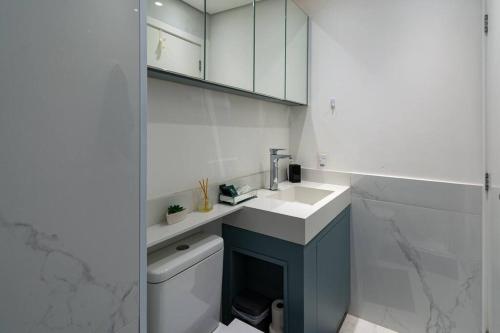 a white bathroom with a sink and a toilet at Apto Brás com piscina próximo ao centro de compras in Sao Paulo
