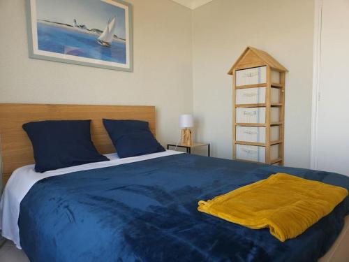 - une chambre avec un lit bleu et une couverture jaune dans l'établissement Maison de vacances vue mer et port plaisance, à La Richemondière