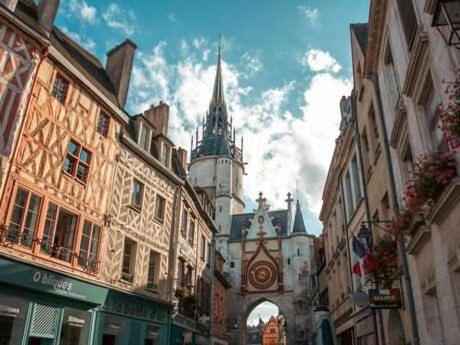 a city street with buildings and a building with a tower at LE CHATEL BOURGEOIS in Appoigny