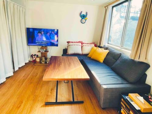 a living room with a blue couch and a wooden table at サクラ in Tokyo