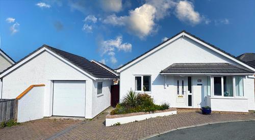 a white house with a garage on a street at CYNEFIN- 3 Bed, 2 Bath-1 x En-Suite, DETCAHED BUNGLAOW- PET FRIENDLY in Trearddur