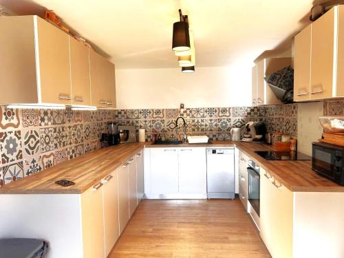 a kitchen with white cabinets and wooden counter tops at La Vendegeoise - Gîte chaleureux 10P chez l'habitant - Jardin- Piscine ext chauffée partagée de mai à septembre in Vendegies-au-Bois