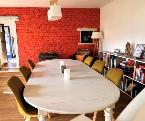 a dining room table with chairs and a brick wall at La Vendegeoise - Gîte chaleureux 10P chez l'habitant - Jardin- Piscine ext chauffée partagée de mai à septembre in Vendegies-au-Bois