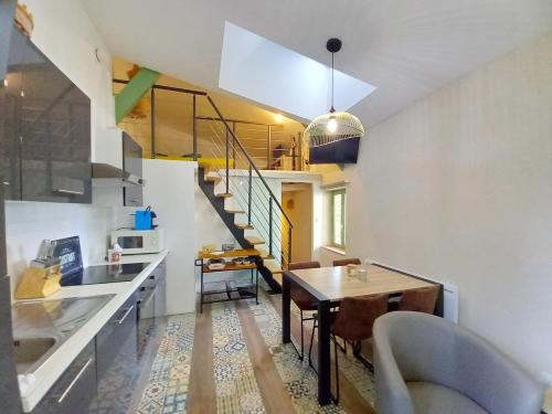 a kitchen and living room with a table and a staircase at Le gîte du mas avec piscine in Bourganeuf