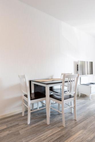 a dining room table with two chairs and a white wall at Santa's Holiday Homes in Rovaniemi