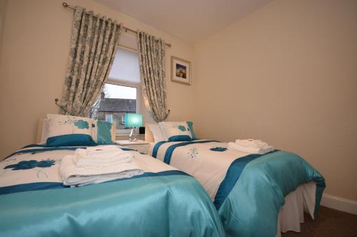 two twin beds in a room with a window at Wallace Apartment in Stirling