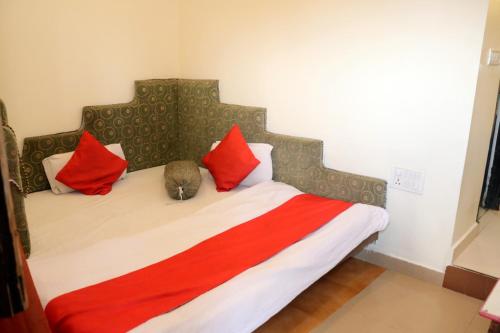 a bedroom with a bed with red pillows at Hotel utkarsh in Pachmarhī