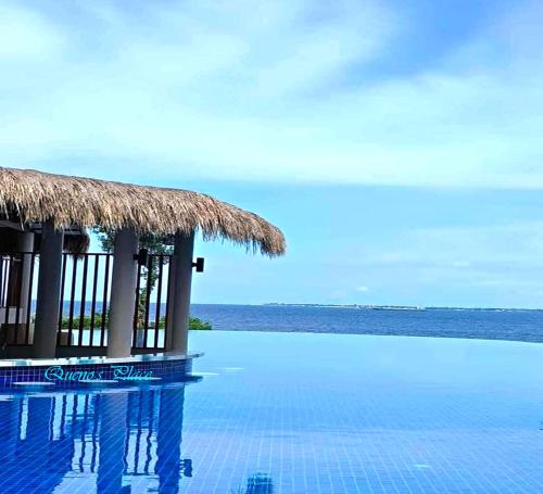 a swimming pool with a straw hut next to the ocean at Mactan Newtown - New Modern Condo with Ocean View in Mactan