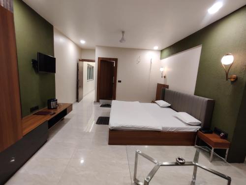 a bedroom with a bed and a desk and a television at Hotel utkarsh in Pachmarhī
