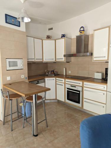 une cuisine avec des armoires blanches et une table en bois dans l'établissement villa bord de mer, à Torreilles