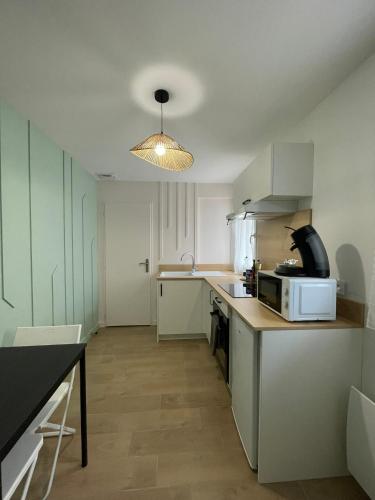 une cuisine avec des armoires blanches et un micro-ondes dans l'établissement Léo - Cosy Studio entièrement rénové avec courette, à Vichy