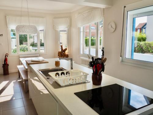 een witte keuken met een wastafel en ramen bij Villa Gisèle in Le Touquet-Paris-Plage