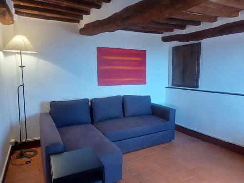 a living room with a blue couch and a lamp at Casa alla porta con panorama in Montecastelli Pisano