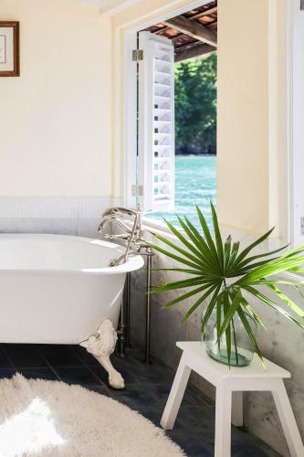 a bathroom with a white tub and a potted plant at Jamaica Inn in Ocho Rios