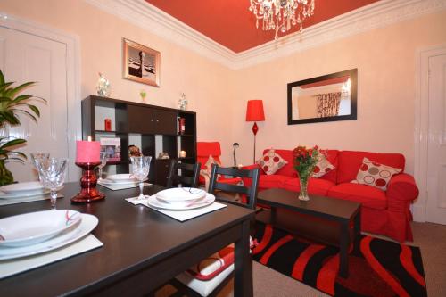 a living room with a red couch and a table at Wallace Apartment in Stirling