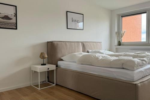 a white bedroom with a large bed and a window at Cozy apartment with balcony in Lehre