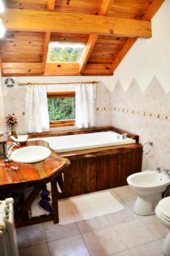 a bathroom with a tub and a toilet and a sink at Apart Hotel y Hosteria del Sir in Villa La Angostura