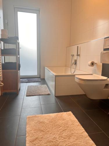 a bathroom with a tub and a toilet and two rugs at Modernes City-Apartment - Top-Lage in Nürnberg in Nürnberg