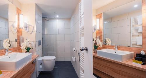 a bathroom with two sinks and a toilet at PLAZA Premium Columbus Bremen in Bremen