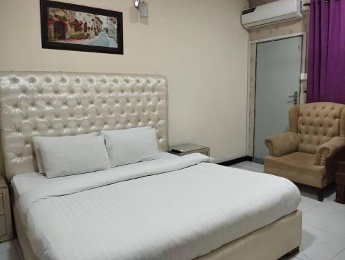 Un dormitorio con una gran cama blanca y una silla. en Travel Inn islamabad, en Islamabad
