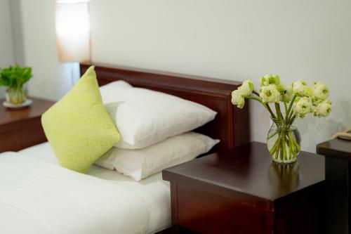 a bed with a vase of flowers on a table at Skyline Boutique Hotel in Phnom Penh