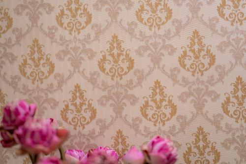 two pink flowers in front of a wall with wallpaper at Skyline Boutique Hotel in Phnom Penh