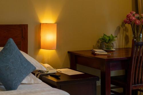 a bedroom with a desk and a bed and a table with a lamp at Skyline Boutique Hotel in Phnom Penh