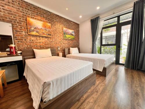 a bedroom with two beds and a brick wall at Tam Coc Boutique Garden in Ninh Binh