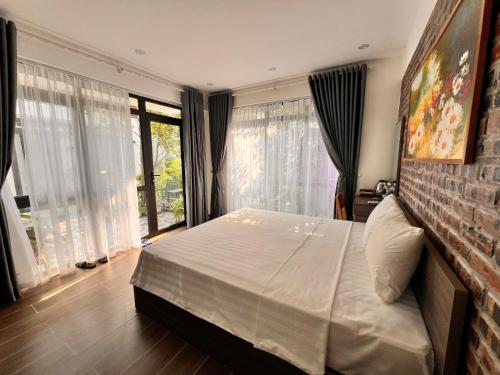 a bedroom with a large bed and large windows at Tam Coc Boutique Garden in Ninh Binh