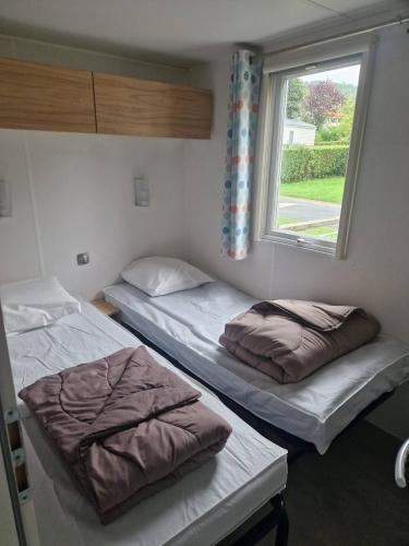 deux lits dans une chambre avec une fenêtre dans l'établissement Camping 5 étoiles piscines chauffées club enfants mobilhome premium 6pers, à Houlgate