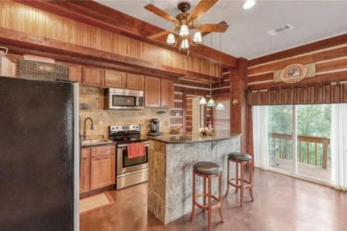 a kitchen with wooden cabinets and a ceiling fan at RUSTIC ARMADILLO CABIN with VIEW BY HIDDEN FALL PARK, Fenced yard for Dogs in Smithwick