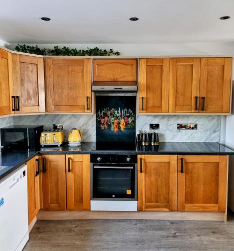 a kitchen with wooden cabinets and black counter tops at 2 Bed Cosy House in London by Zaftastic Stays in London