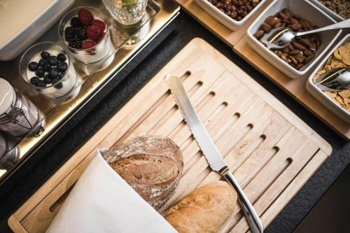 a counter with a cutting board with bread and a knife at Christophorus Mountain Residence in San Vigilio Di Marebbe