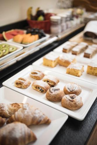 a display case with trays of pastries and other pastries at Christophorus Mountain Residence in San Vigilio Di Marebbe