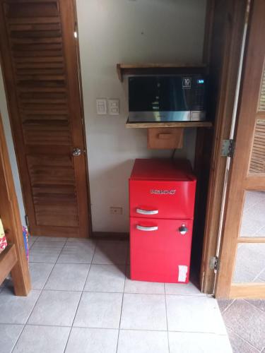 a red refrigerator with a microwave on top of it at Paradise Point Villas in Castara