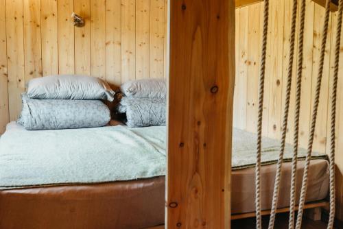 a bed in a wooden room with two pillows at Beneháti kunyhók in Matrafured