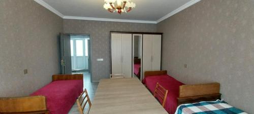 a room with two beds and a table in it at Qonaq evi quest home in Sheki