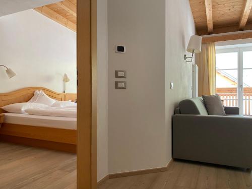 a bedroom with a bed and a couch and a window at Christophorus Mountain Residence in San Vigilio Di Marebbe