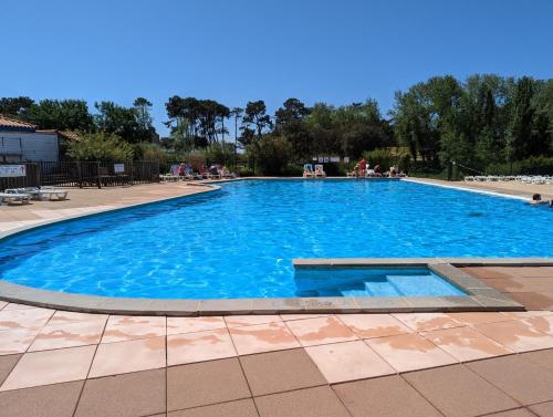 une grande piscine bleue avec des personnes assises autour de celle-ci dans l'établissement Appart. 6 pers. avec piscine, à Talmont-Saint-Hilaire